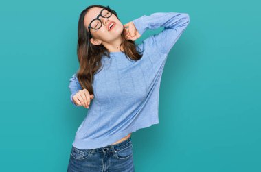 Genç ve güzel bir kadın gündelik kıyafetler ve gözlük takıyor. Yorgun ve rahat, uykulu ve sabahın erken saatleri için esniyor. 