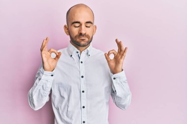 Günlük kıyafetler giyen genç İspanyol adam rahatla ve gözleri kapalı gülümse parmaklarıyla meditasyon hareketi yapıyor. yoga konsepti. 