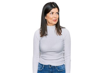 Güzel esmer kadın günlük kıyafetler giyiyor gülümsüyor yan tarafa bakıyor ve düşünüyor.. 