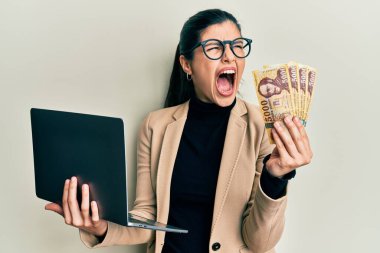 Genç İspanyol kadın iş stili dizüstü bilgisayar ve Macar forint 'i tutuyor kızgın ve öfkeli çığlıklar atıyor, öfkeyle bağırıyor. öfke ve agresif konsept. 