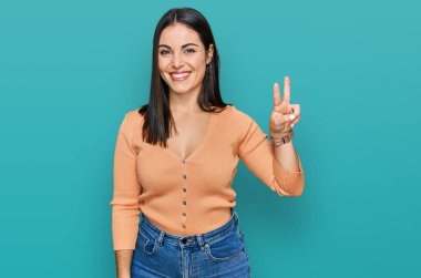 Gündelik kıyafetler giyen genç İspanyol kadın kameraya bakıp zafer işareti yapıyor. İki numara.. 