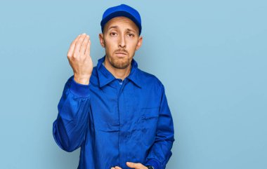 Kel, sakallı, işçi tulumu giyen, İtalyan jestleri yapan, kendine güveni tam bir ifade sergileyen bir adam. 