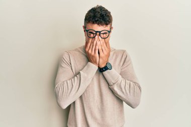 Balıkçı yaka kazak giyen İspanyol genç adam yorgunluk ve baş ağrısı için gözlerini ovuşturuyor, uykulu ve yorgun bir ifade takınıyor. görme sorunu 