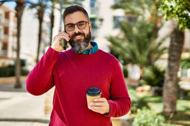 Genç İspanyol yönetici akıllı telefonda konuşuyor. Şehirde kahve içiyor..