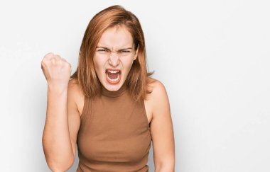 Kafkasyalı genç bir kadın günlük kıyafetler giyiyor kızgın ve kızgın yumruğunu kaldırıyor ve öfkeyle bağırıyor. öfke ve agresif konsept. 