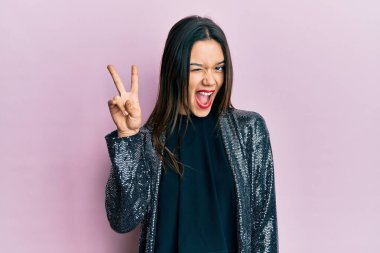 Parti ceketi giyen, gülümseyen, kameraya göz kırpan genç İspanyol kız zafer işareti yapıyor. İki numara.. 