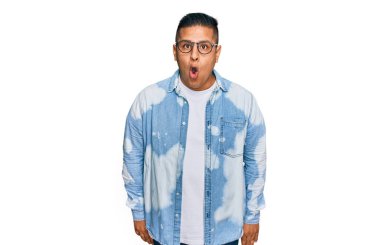 Gündelik kıyafetler giyen, gözlüklü, ağzı açık, korkmuş ve şaşırmış bir genç adam. 