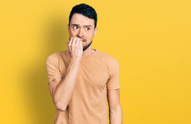 Sakallı, sıradan tişörtlü İspanyol bir adam. Ağzı tırnak yiyen elleri yüzünden gergin ve stresli görünüyor. anksiyete. 