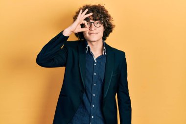 İş ceketi ve gözlük takan yakışıklı genç adam gülümsüyor. 