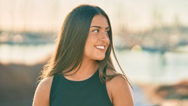 Genç İspanyol kız gülümseyerek şehirde mutlu mesut dikiliyor..