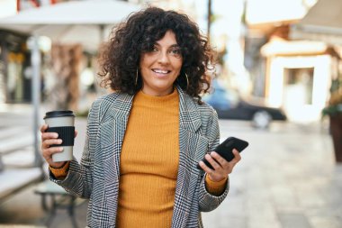 Genç İspanyol iş kadını akıllı telefon kullanıyor. Şehirde kahve içiyor..