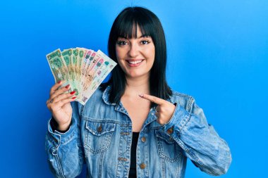 Birleşik Arap Emirlikleri 'ni elinde tutan genç İspanyol kadın dirhem banknotları mutlu bir şekilde parmakla işaret ediyor. 