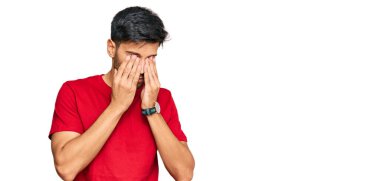 Genç yakışıklı adam, günlük kırmızı tişört giyiyor yorgunluk ve baş ağrısı için gözlerini ovuşturuyor, uykulu ve yorgun bir ifade takınıyor. görme sorunu 