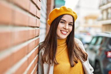 Genç İspanyol kız gülümseyerek şehirde mutlu mesut dikiliyor..