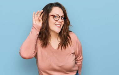 Gündelik kıyafetler ve gözlük takan, ağzı kulaklarında gülümseyen, dedikoduları ve dedikoduları dinleyen genç bir kadın. Sağırlık kavramı. 