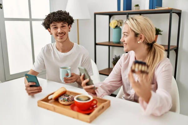 Pareja Joven Desayunando Usando Smartphone Casa —  Fotos de Stock