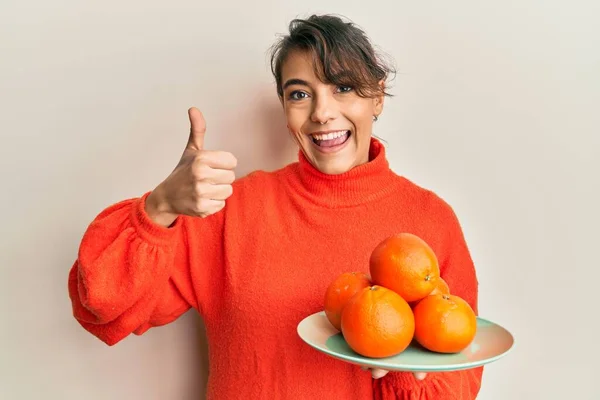 Jovem Hispânica Segurando Laranjas Frescas Sorrindo Feliz Positivo Polegar Para — Fotografia de Stock