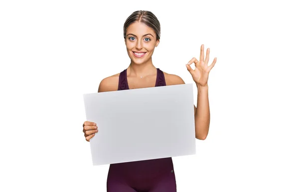 Beautiful Blonde Woman Wearing Sportswear Holding White Banner Doing Sign — Stock Photo, Image