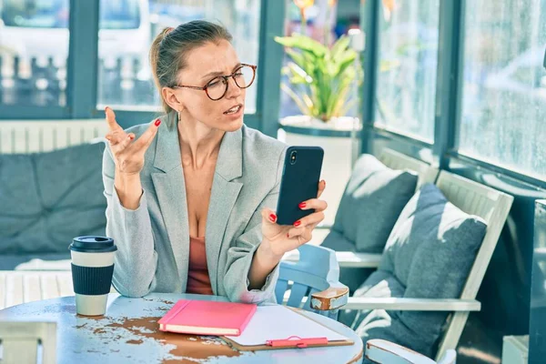 年轻的金发女商人在咖啡店用智能手机做视频通话 — 图库照片