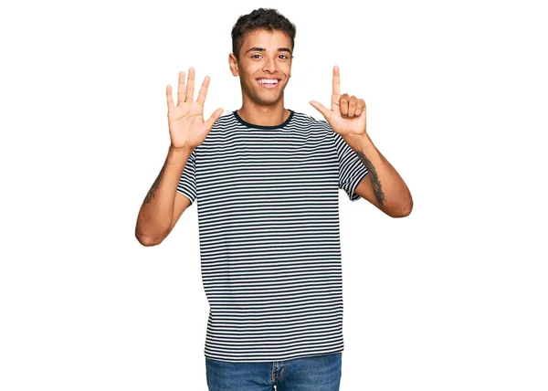 若いですハンサムなアフリカ系アメリカ人男性身に着けているカジュアル服を見せ 指番号7で指摘しながら笑顔自信と幸せ — ストック写真
