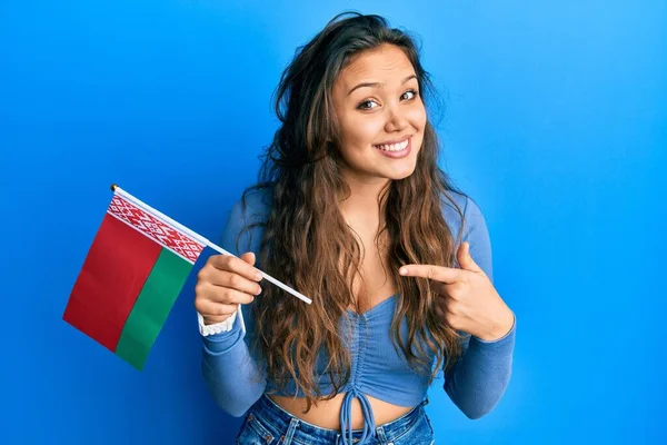 Młoda Latynoska Dziewczyna Trzyma Flagę Belarus Uśmiechając Się Szczęśliwy Wskazując — Zdjęcie stockowe
