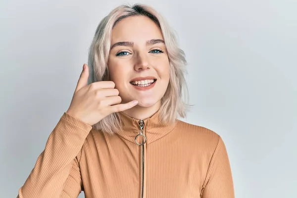 Ung Blondine Pige Iført Afslappet Tøj Smilende Laver Telefon Gestus - Stock-foto