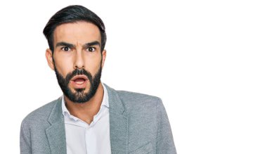 Şok olmuş, iş kıyafetleri giymiş genç İspanyol bir adam şüpheci ve alaycı görünüyor, ağzı açık kalınca şaşırıyor. 