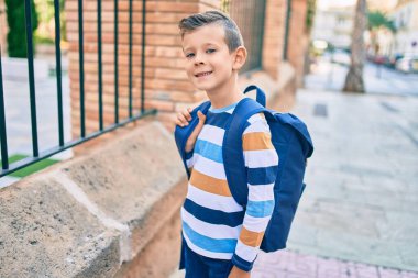 Sevimli beyaz bir öğrenci şehirde mutlu bir şekilde gülümsüyor..