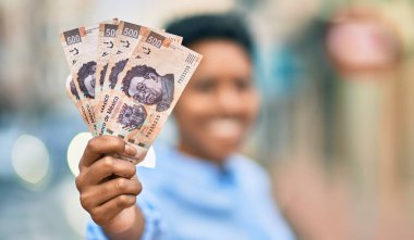 Genç Afrikalı Amerikalı kız gülümsüyor. Meksika 500 pesosunu şehirde tutuyor..