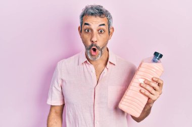 Gri saçlı, elinde deterjan şişesi olan yakışıklı, orta yaşlı bir adam. Şaşırmak için ağzı açık, korkmuş ve hayrete düşmüş. İnanmayan yüz. 