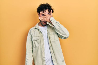 Gündelik kıyafetler giyen genç İspanyol adam şok içinde yüzünü ve gözlerini kapayarak utanmış ifadesiyle parmaklarından bakıyor.. 