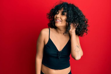 Kolsuz tişörtlü, sıradan giyinen, ağzı kulaklarında dolaşan dedikoduları ve dedikoduları dinleyen genç İspanyol kadın. Sağırlık kavramı. 