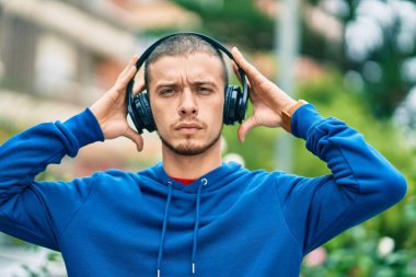 Şehirde kulaklık takan ciddi bir suratı olan genç bir İspanyol.