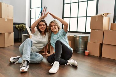 Genç çift yeni evlerinde kollarını kaldırarak ev sembolü yapıyor..