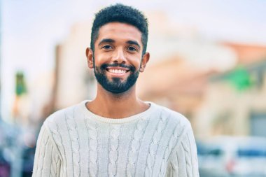 Genç Afrikalı Amerikalı adam gülümseyerek şehirde mutlu mesut duruyor..