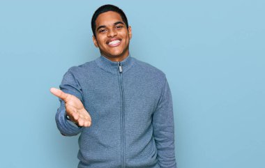 Genç, yakışıklı, günlük eşofman üstü giyen neşeli gülümsemeli, yardım eli uzatan ve kabul gören bir İspanyol.. 