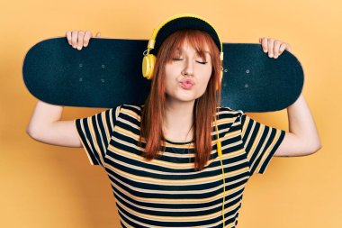 Kızıl saçlı, kulaklık takmış, kameraya bakıp öpüşen güzel ve seksi bir kadın. aşk ifadesi. 