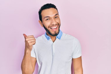 Sakallı, sıradan beyaz tişörtlü İspanyol bir adam baş parmağını yukarı kaldırıyor ve ağzı açık gülümsüyor. 