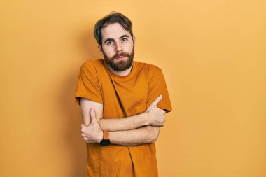 Sakallı, sıradan sarı tişörtlü, kışın soğuktan titriyor ve donuyor. Yüzünde üzgün ve şok edici bir ifade var. 