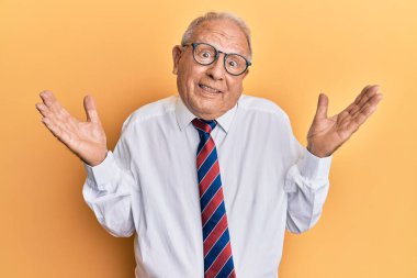 İş kıyafetleri giyen, kafası karışmış, kolları açık, hiçbir fikri olmayan, şüpheli yüzlü beyaz bir adam.. 