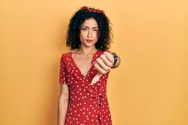 Yazlık elbise giyen genç Latin kız mutsuz ve kızgın görünüyor. Reddedildiğini gösteriyor ve olumsuz bir hareket yapıyor. kötü ifade. 