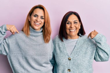 Latin anne ve kızı gündelik giysiler giyiyorlar. Kendine güveniyorlar. Gülümsüyorlar ve gururlu ve mutlular.. 