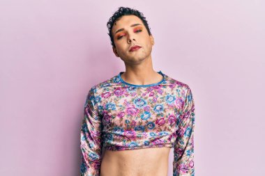 Makyaj yapan yakışıklı bir adam. Moda kıyafetleri giyiyor. Yüzünde ciddi bir ifade var. Basit ve doğal bir şekilde kameraya bakıyorsun.. 