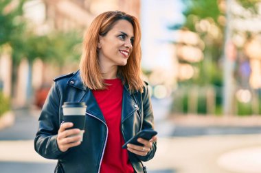 Genç Latin kadın akıllı telefon kullanıyor ve şehirde kahve içiyor..