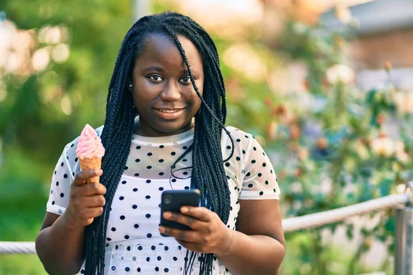 年轻的非洲裔美国女人在城市里用智能手机吃冰激凌 — 图库照片