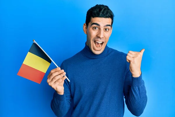 Hombre Hispano Guapo Sosteniendo Bandera Bélgica Señalando Pulgar Hacia Lado —  Fotos de Stock