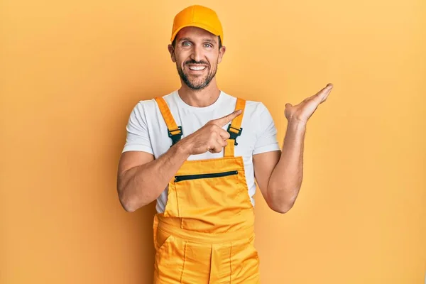 Ung Stilig Man Bär Handyman Uniform Över Gul Bakgrund Förvånad — Stockfoto