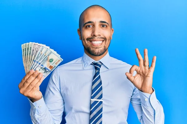 Hispanic Adult Business Man Holding Dollars Doing Sign Fingers Smiling — Stock Photo, Image