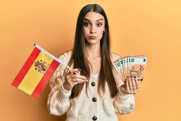 Hermosa Joven Morena Sosteniendo Bandera España Billetes Euros Soplando Mejillas —  Fotos de Stock