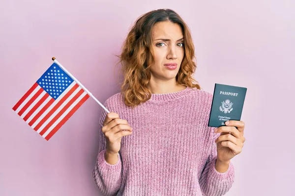 年轻的高加索女人拿着美国国旗和护照 毫无头绪和困惑的表情 怀疑概念 — 图库照片
